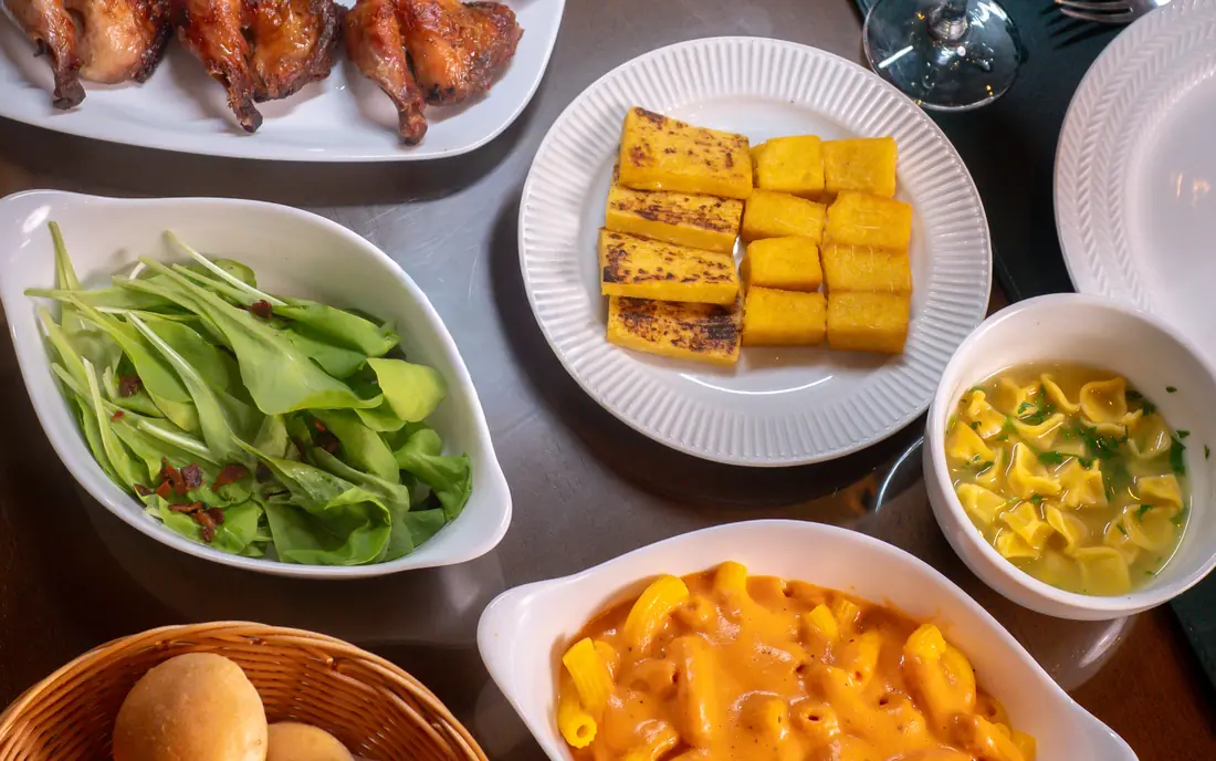 Mesa da sequência com galeto assado, polenta, salada, sopa de capeletti, penne e pão