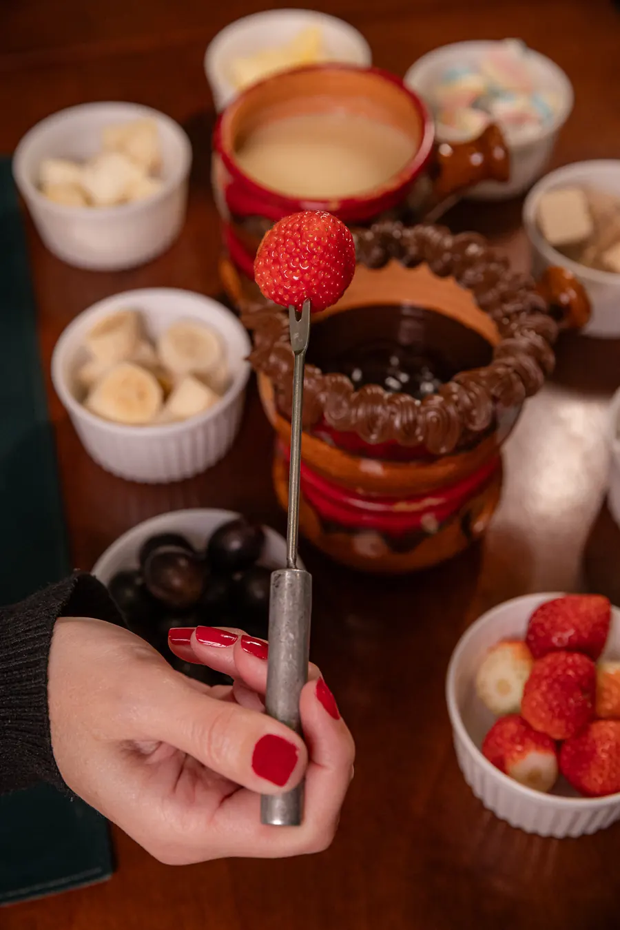 Morango no garfo sendo mergulhado no fondue de chocolate